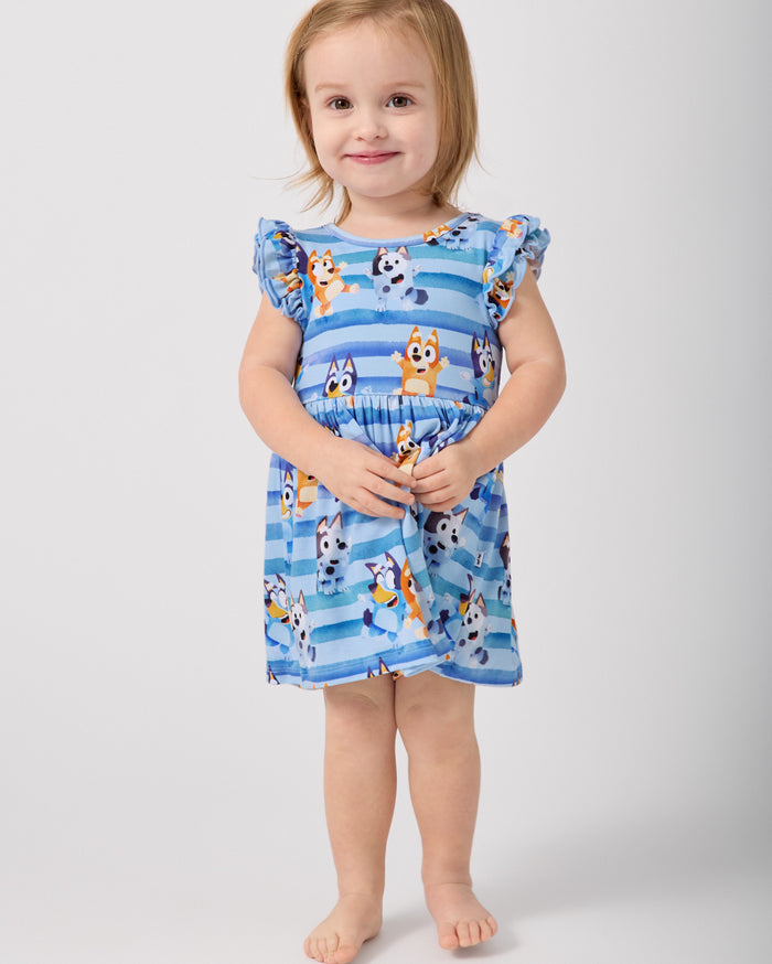 Standing toddler wearing the Bluey Dance All Day Flutter Skater Dress with Bodysuit