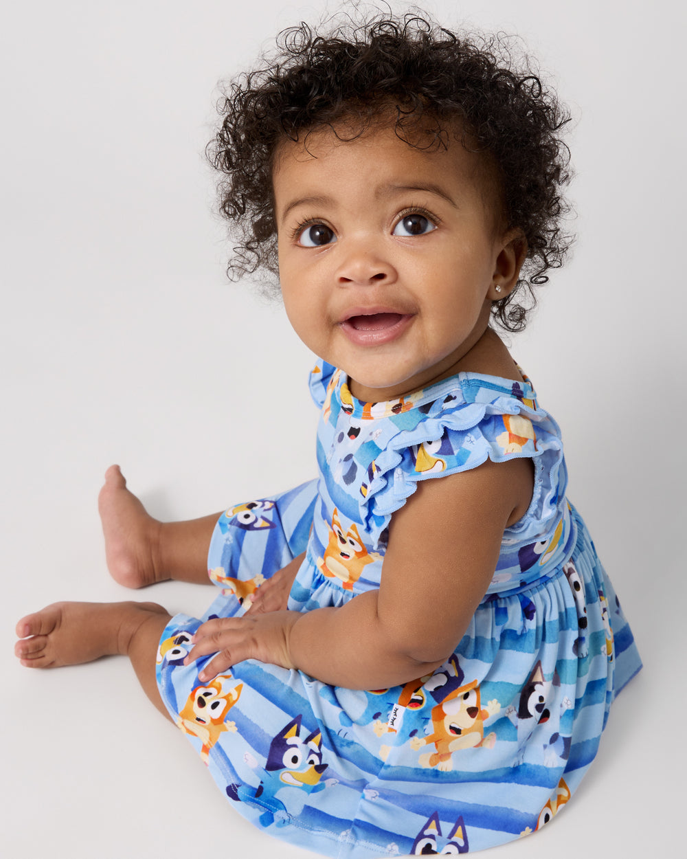 Sitting baby wearing the Bluey Dance All Day Flutter Skater Dress with Bodysuit