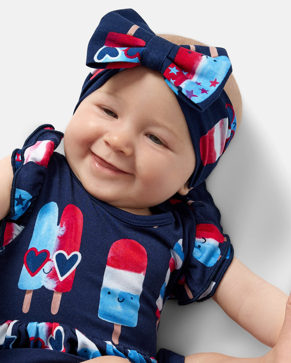 Close up of baby wearing the Sparkle Treats Luxe Bow Headband with a matching Flutter Dress