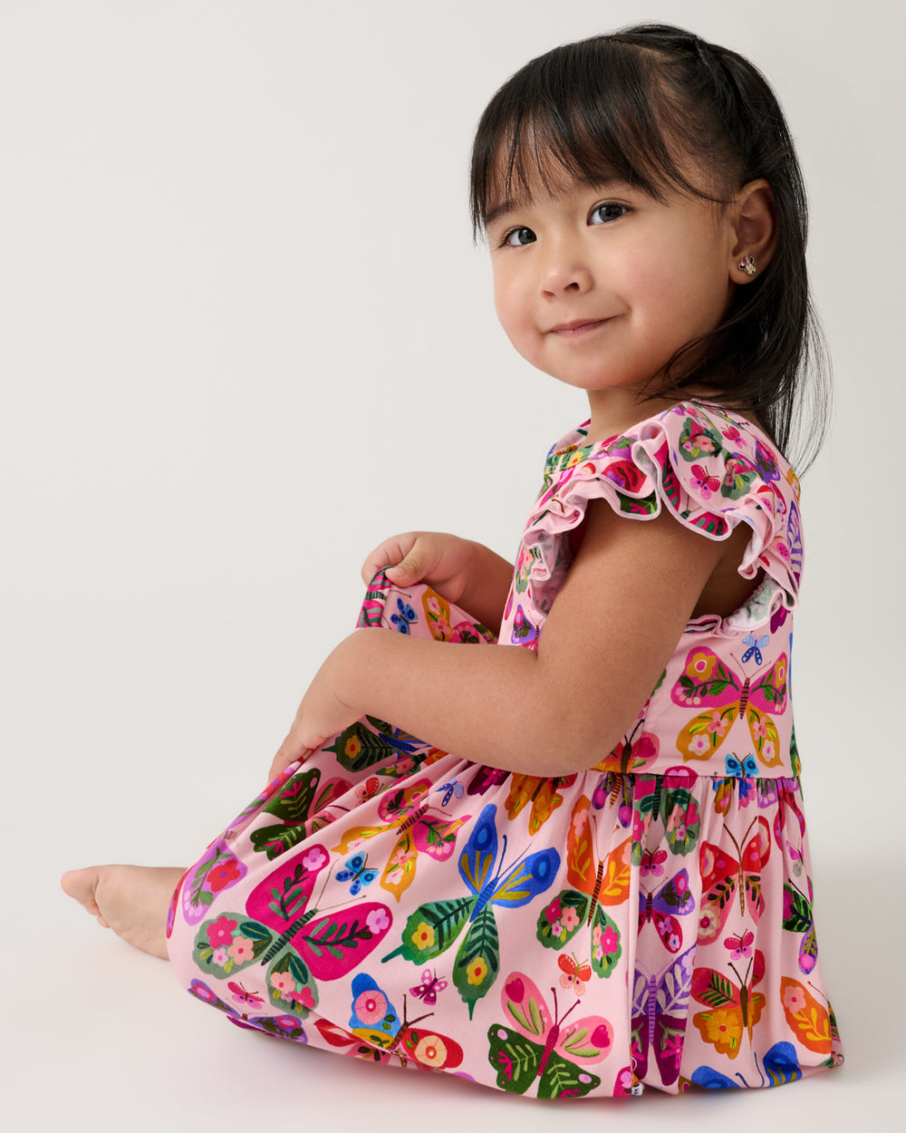 Sitting girl wearing the Flutter Garden Skater Dress with Bodysuit
