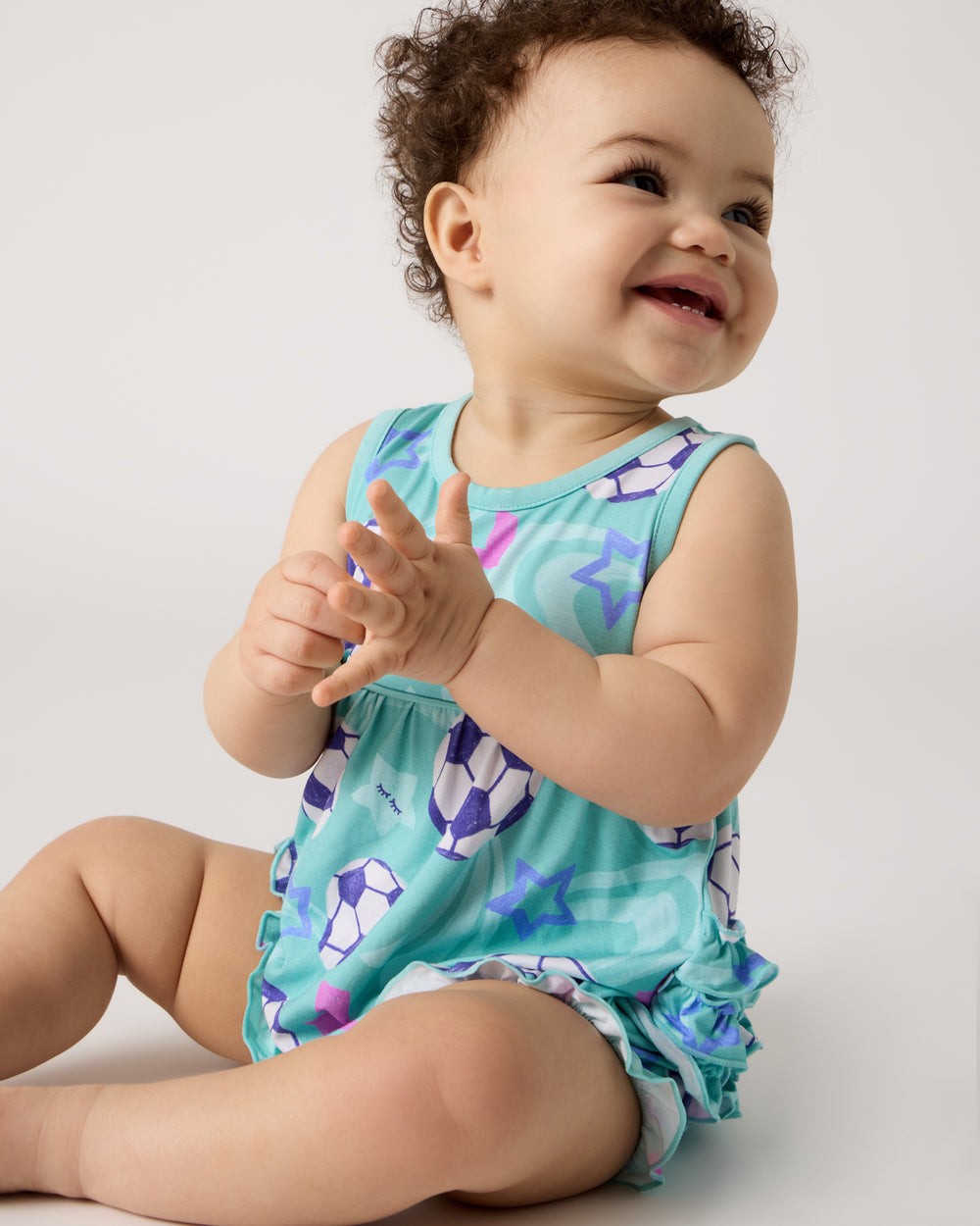 Sitting baby wearing the Aqua Soccer Stars Bubble Romper