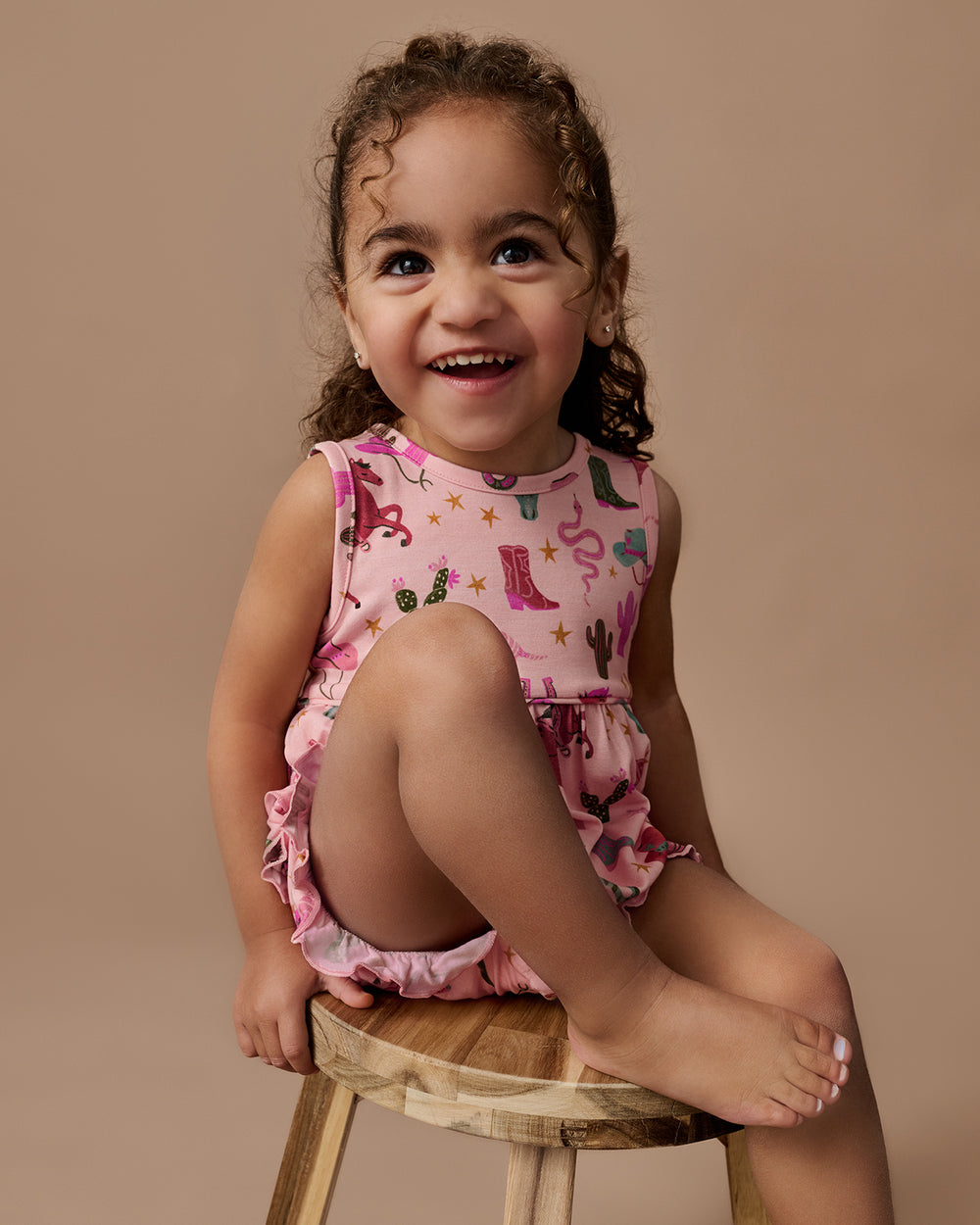 Girl wearing the Pink Rancher Roundup Bubble Romper on a brown background