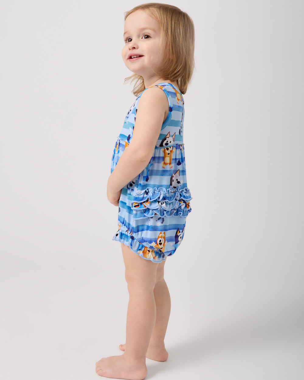 Side view of standing toddler wearing the Bluey Dance All Day Bubble Romper