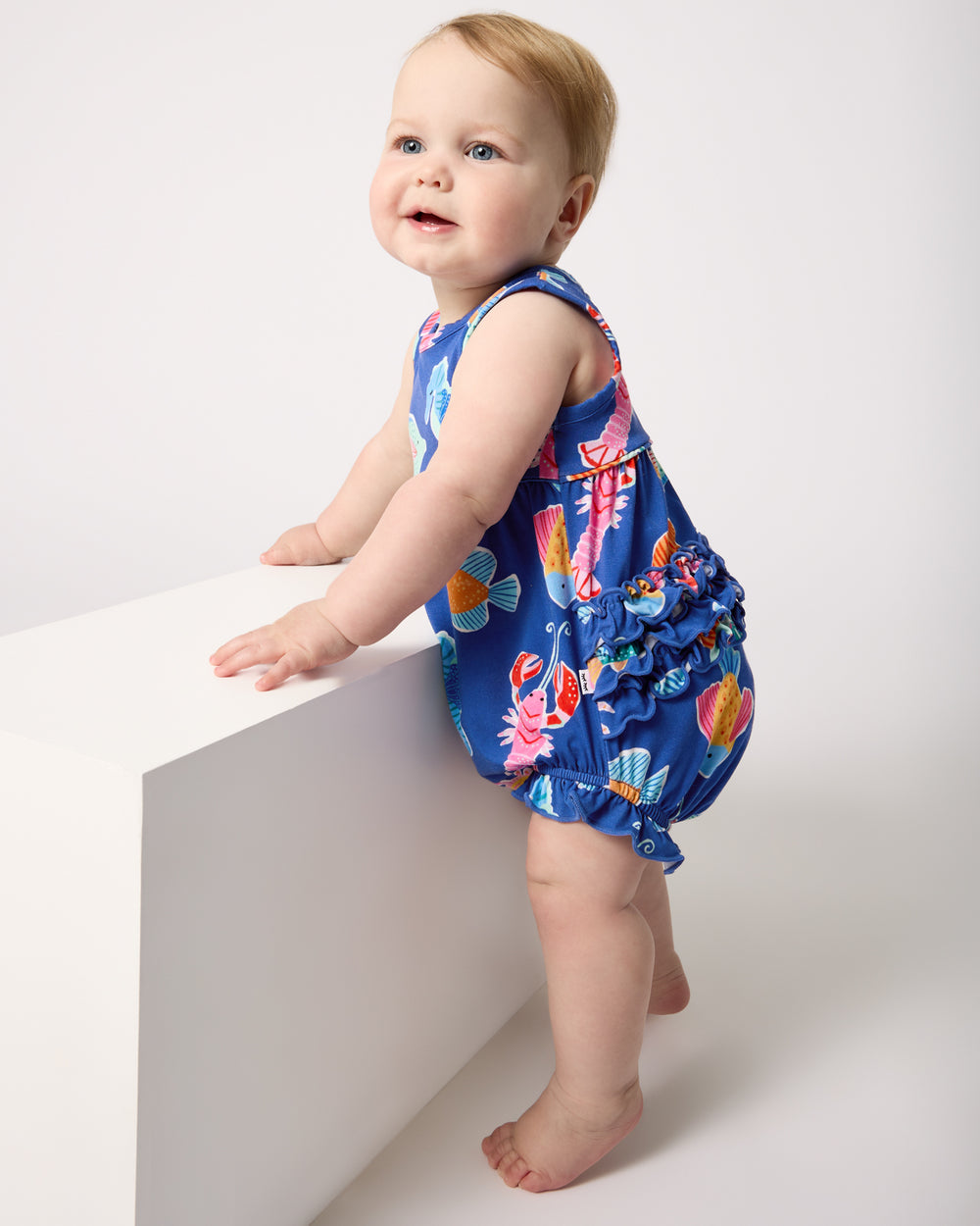 Standing baby wearing the Tidepool Party Bubble Romper