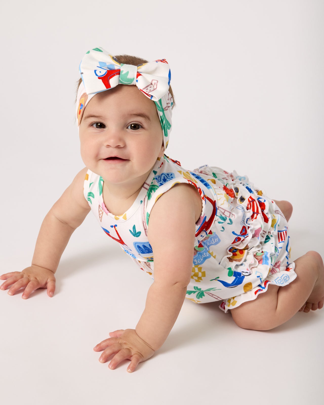 Crawling baby wearing the Ciao Bella Luxe Bow Headband and Bubble Romper