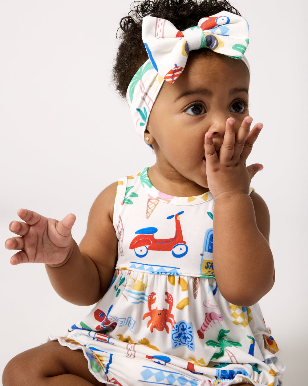 Sitting baby wearing the Ciao Bella Luxe Bow Headband and Bubble Romper