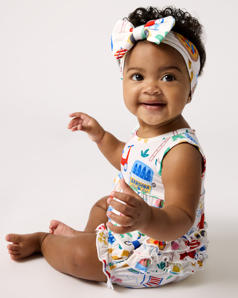 Sitting baby wearing the Ciao Bella Bubble Romper and Luxe Bow
