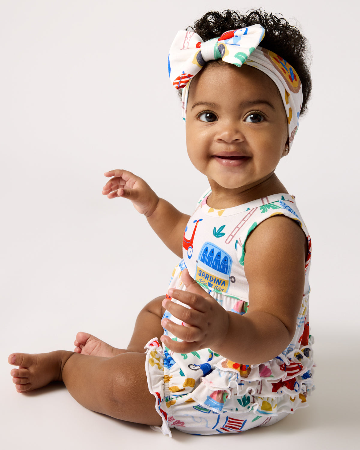 Sitting baby wearing the Ciao Bella Bubble Romper and Luxe Bow