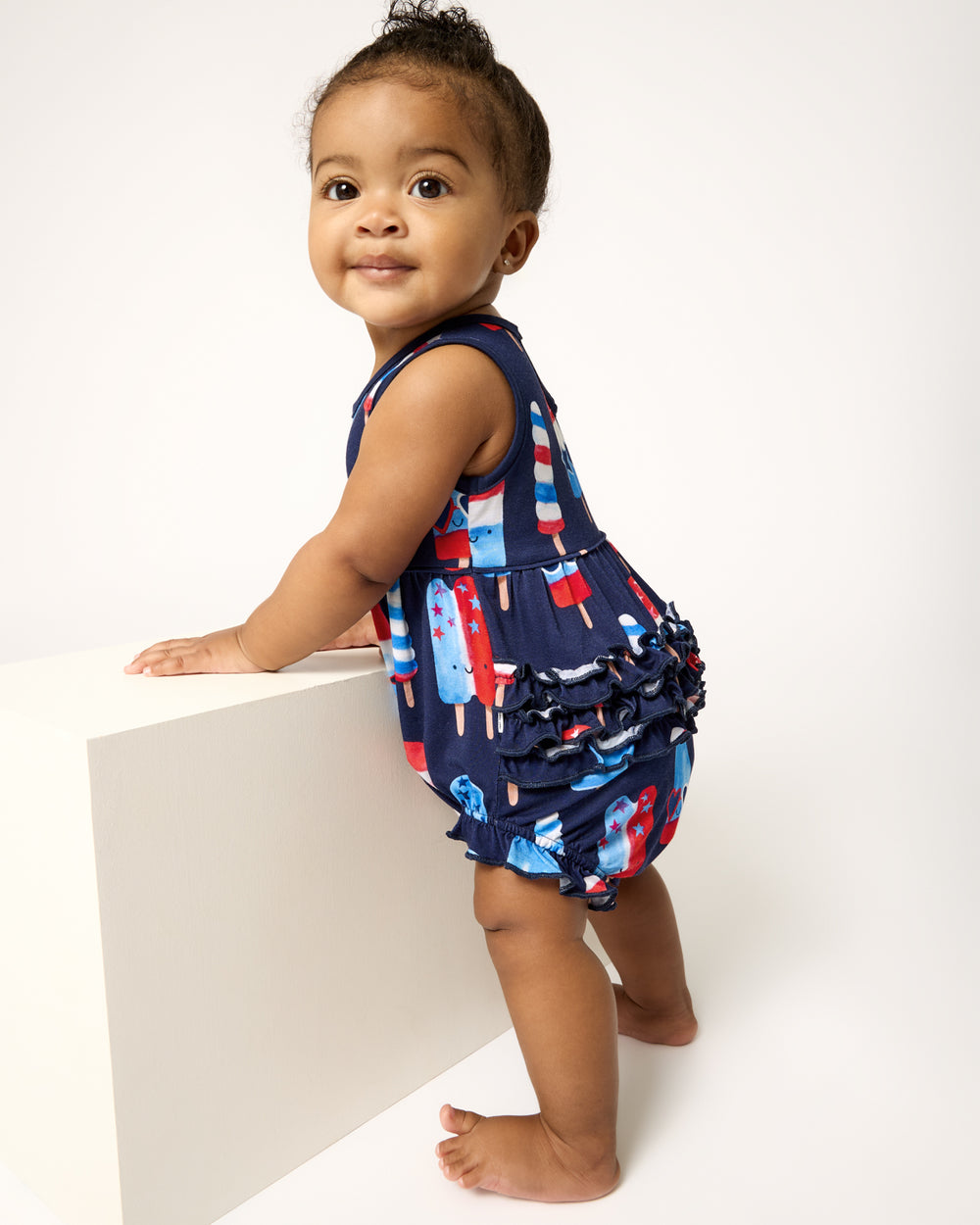 Standing baby wearing the Sparkle Treats Bubble Romper