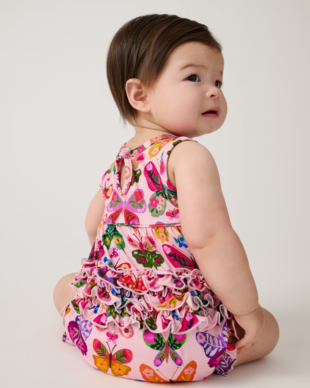 Back view of sitting baby wearing the Flutter Garden Bubble Romper