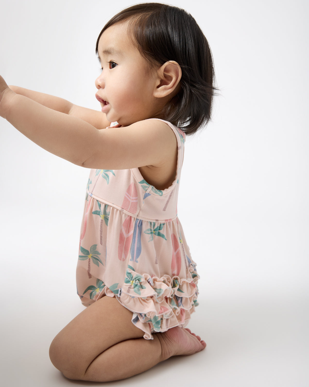 Sitting girl wearing the Palm Dunes Bubble Romper