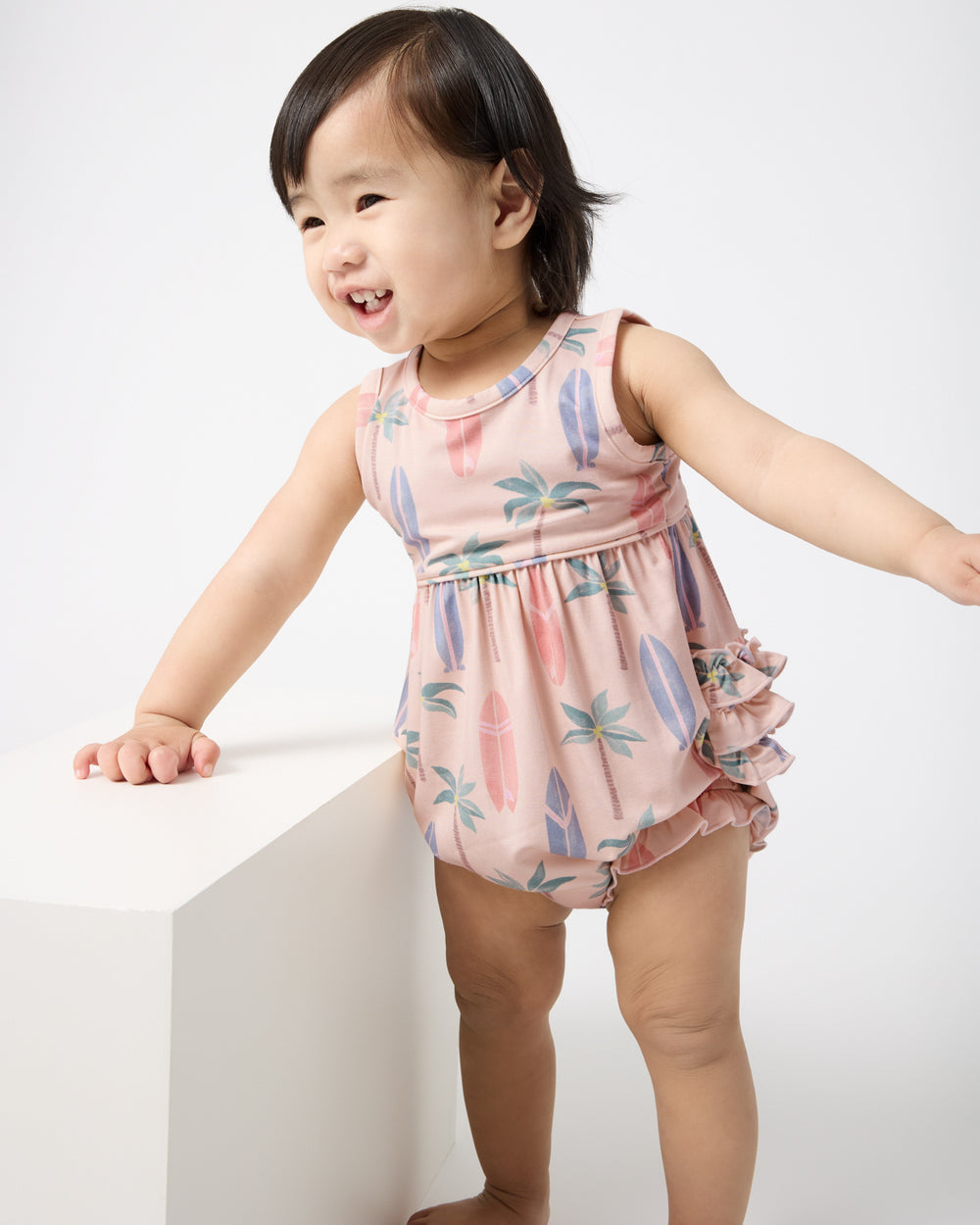 Standing baby wearing the Palm Dunes Bubble Romper