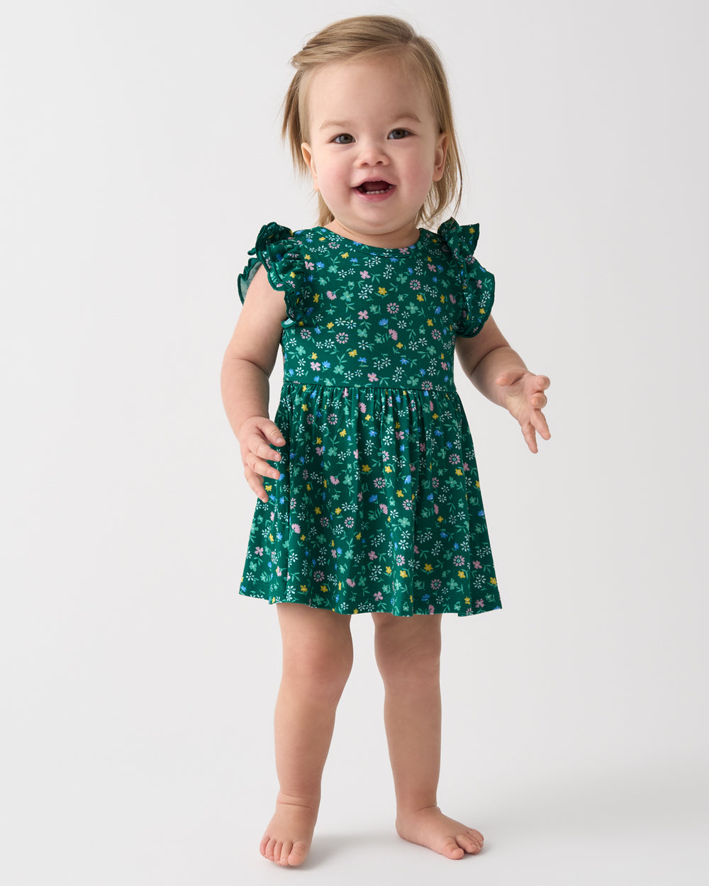 Standing girl wearing the Emerald Meadow Flutter Twirl Dress with Bodysuit