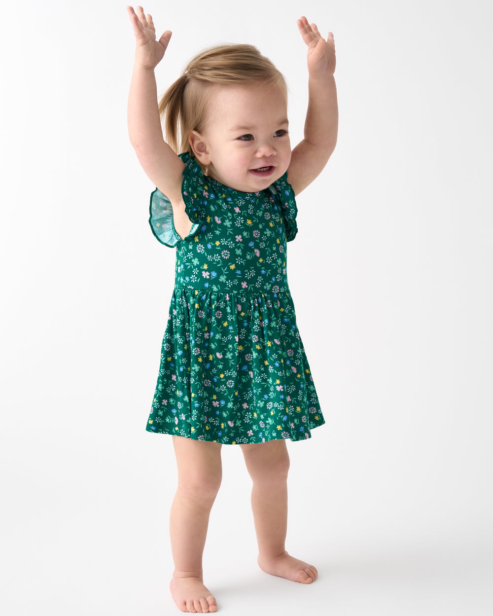 Posing child wearing the Emerald Meadow Flutter Twirl Dress with Bodysuit