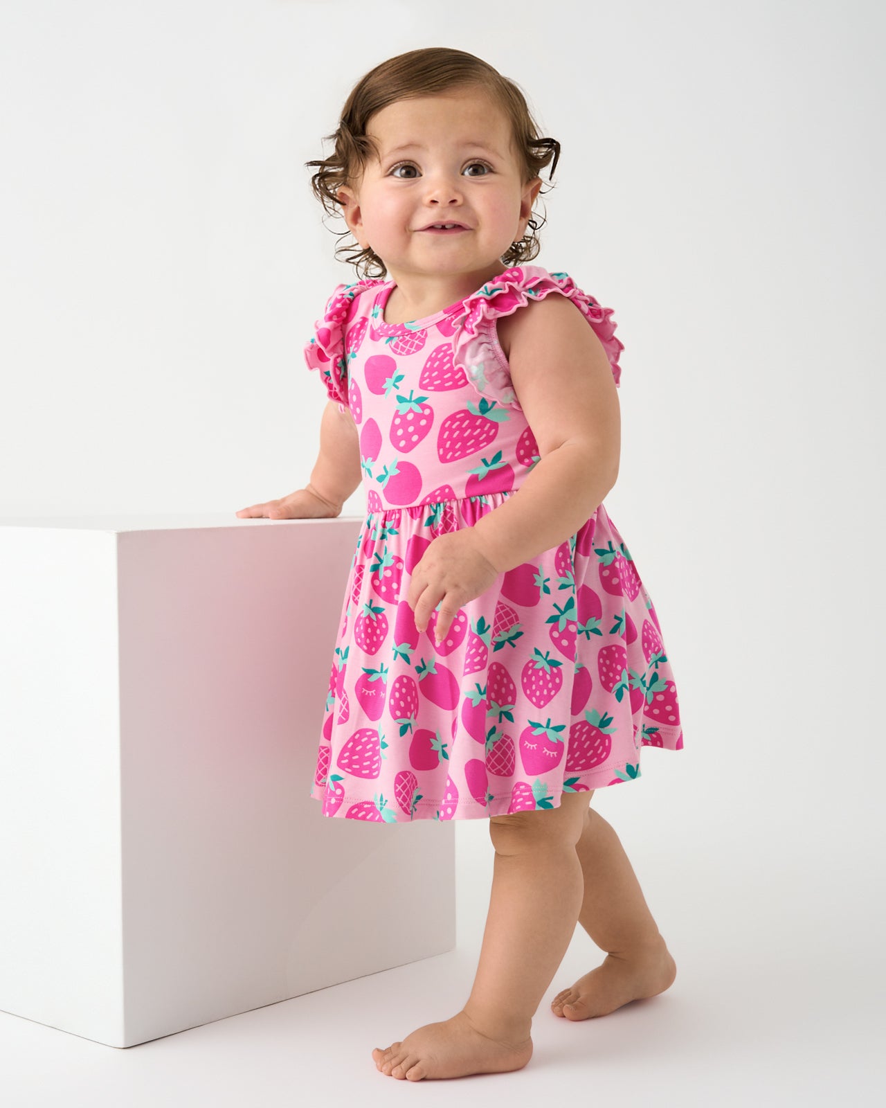 Standing baby wearing the Sweet Strawberries Flutter Twirl Dress with Bodysuit