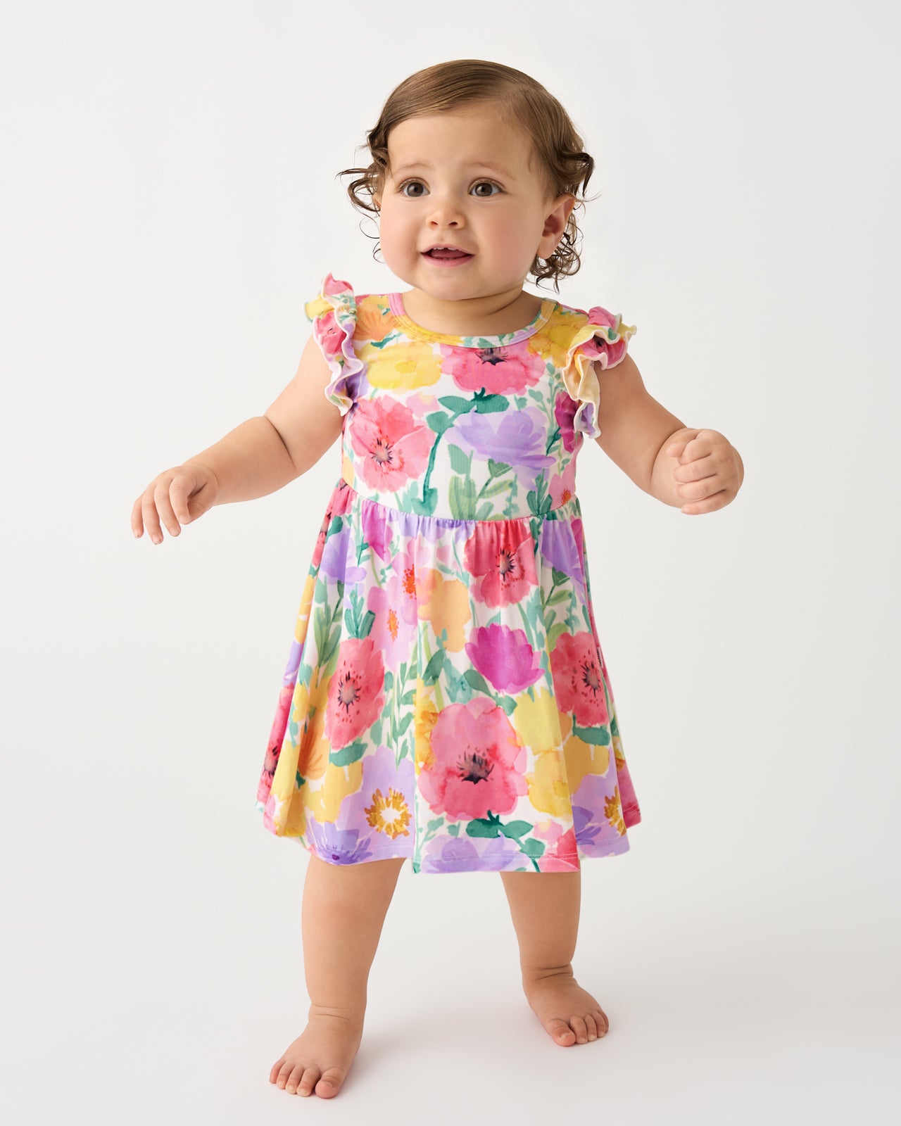 Standing baby wearing the Watercolor Meadow Flutter Twirl Dress with Bodysuit