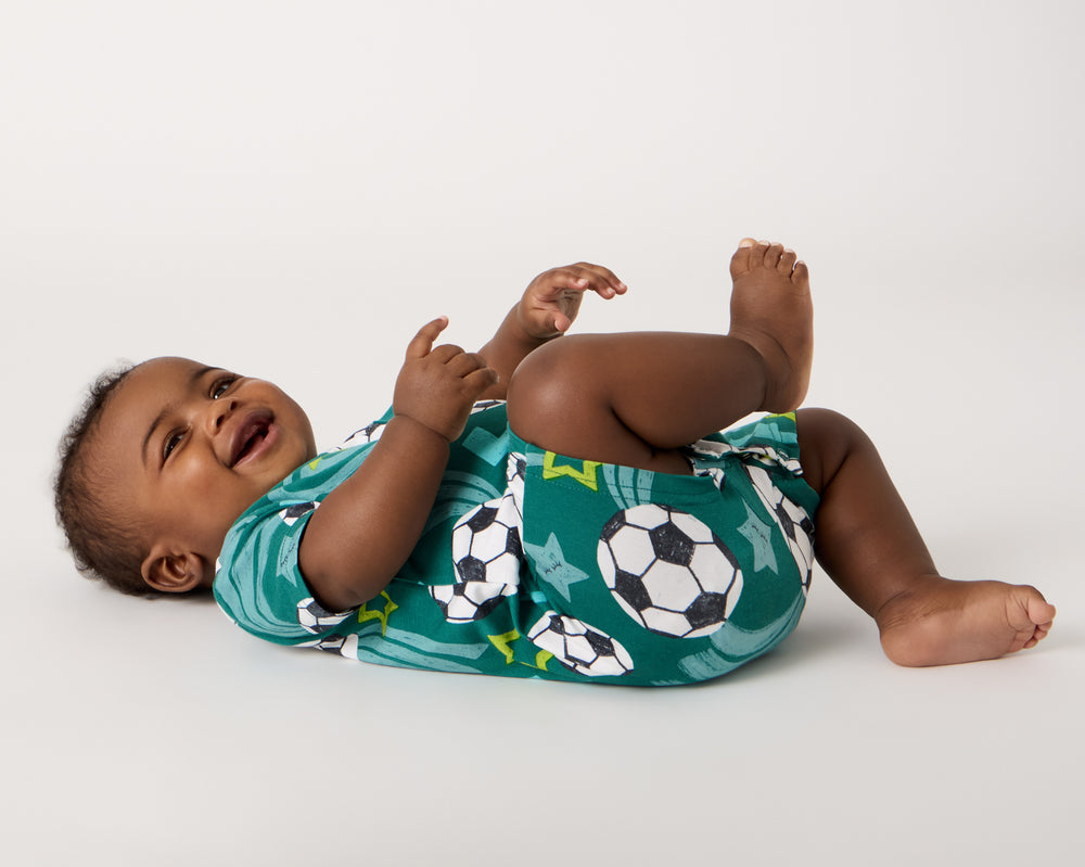 Baby on his back wearing the Soccer Stars Pocket Shorty Romper