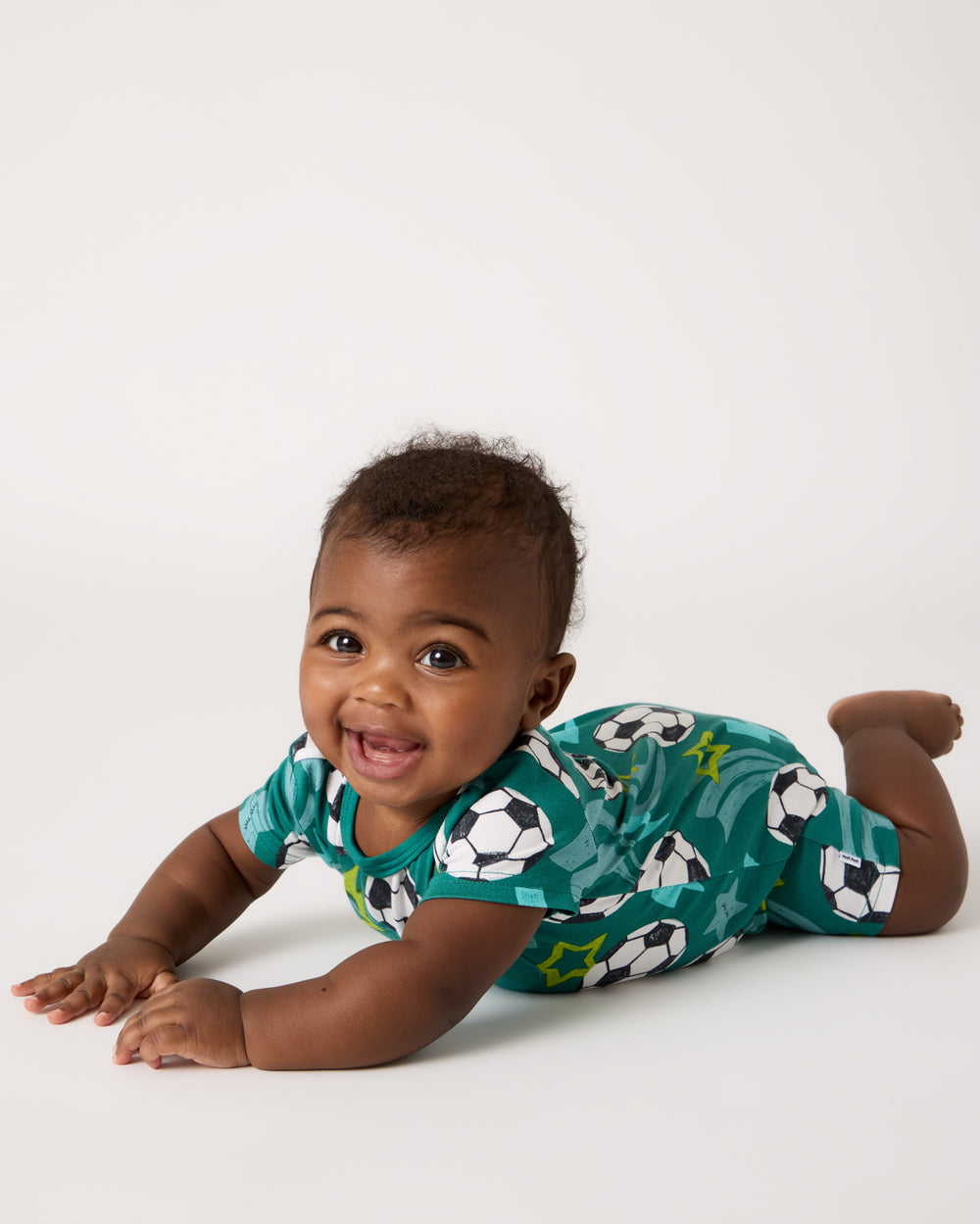 Baby on his tummy wearing the Soccer Stars Pocket Shorty Romper