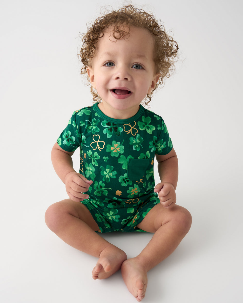 Sitting child wearing the Clover Cuties Pocket Shorty Romper