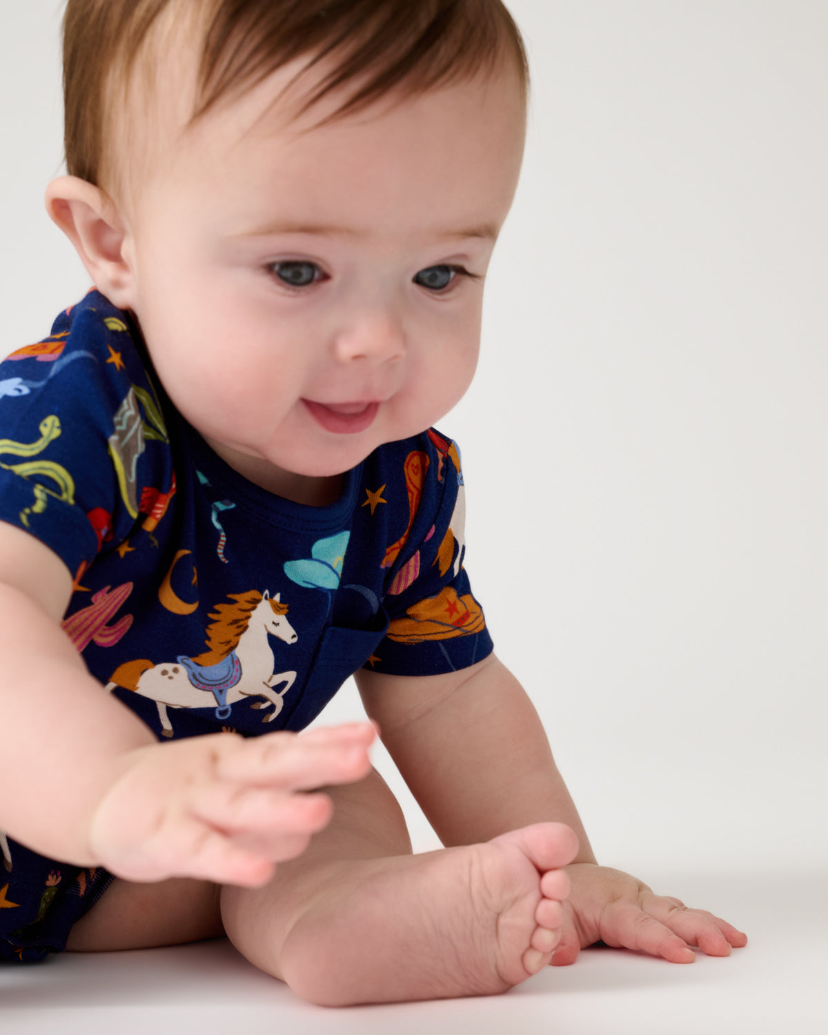 Close up of sitting baby wearing the Blue Rancher Roundup Pocket Shorty Romper
