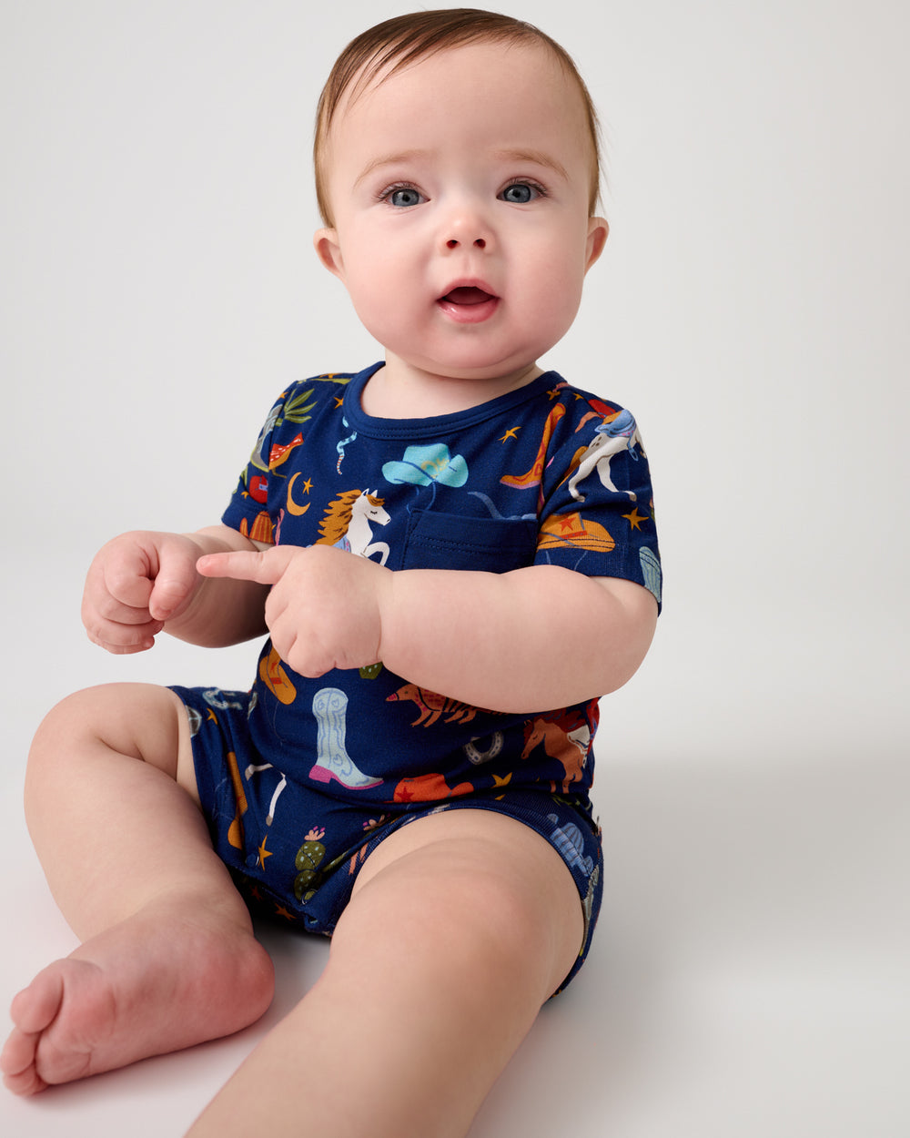 Sitting baby wearing the Blue Rancher Roundup Pocket Shorty Romper