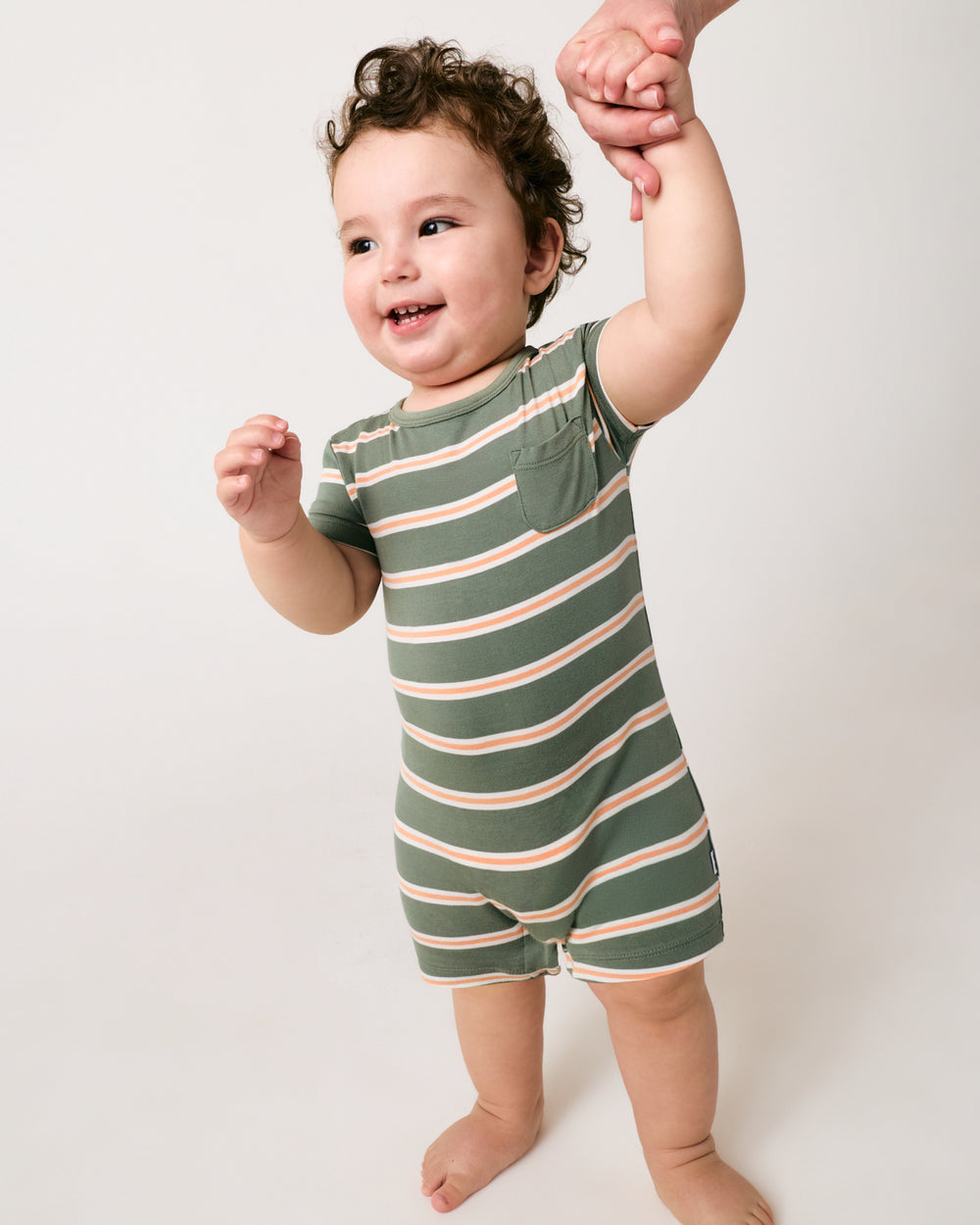 Standing baby wearing the Bold Moss Stripe Pocket Shorty Romper