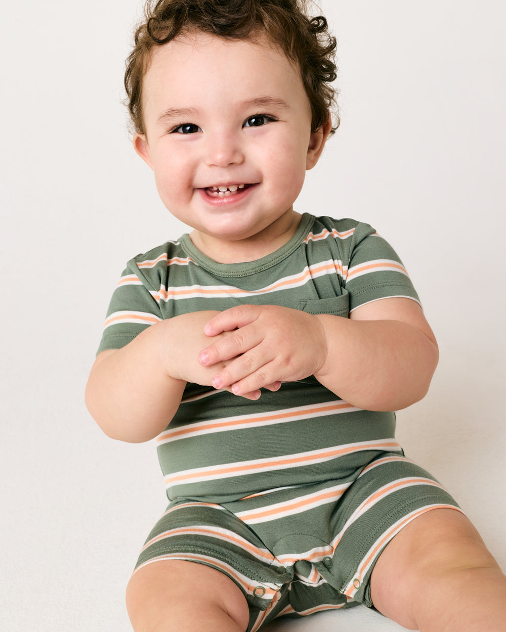Sitting baby wearing the Bold Moss Stripe Pocket Shorty Romper