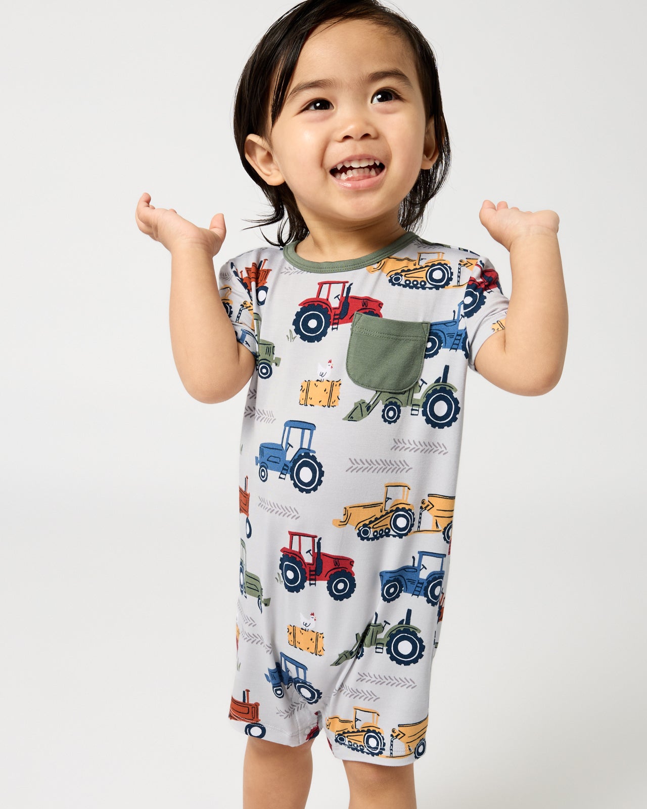 Standing toddler wearing the Tractor Tales Pocket Shorty Romper