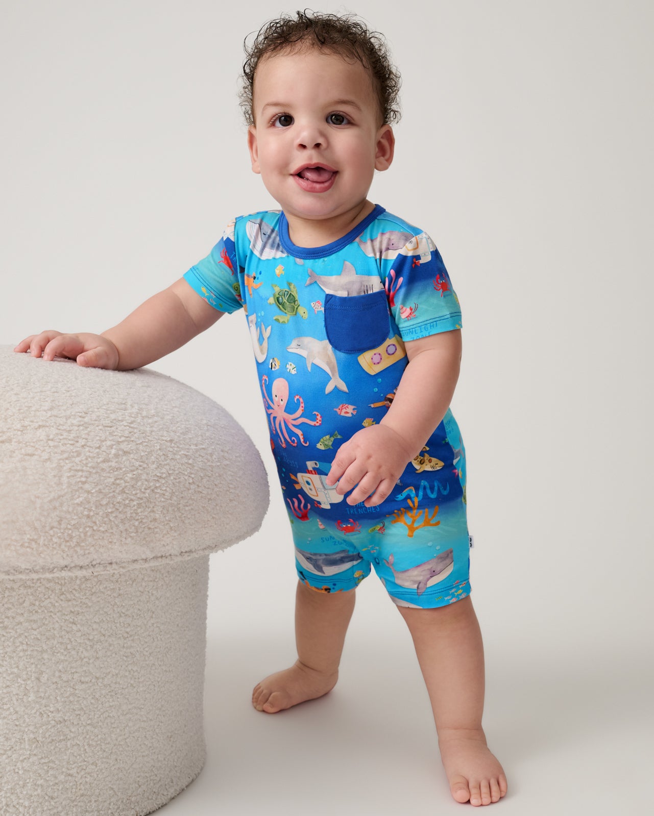 Standing child wearing the Underwater Discovery Pocket Shorty Romper