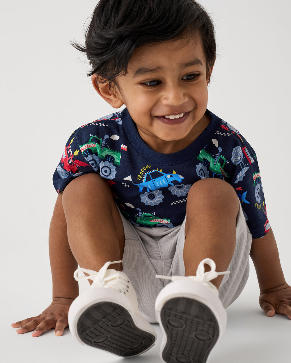 Sitting boy wearing the Monster Truck Madness Relaxed Tee with gray shorts