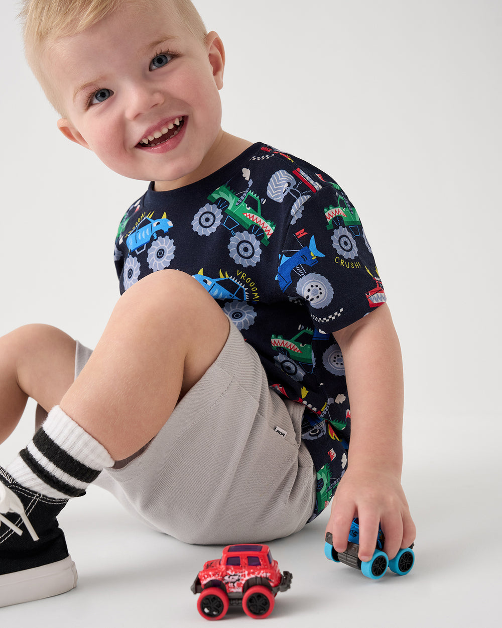 Sitting boy wearing the Monster Truck Madness Relaxed Tee playing with toy trucks