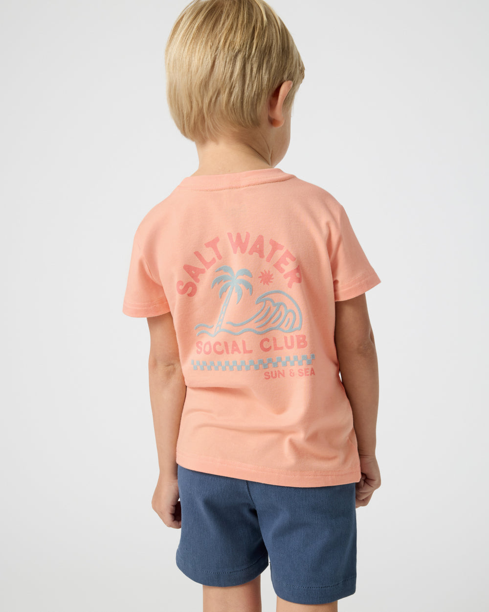 Back view of boy wearing the Salt Water Social Club Relaxed Tee with navy shorts