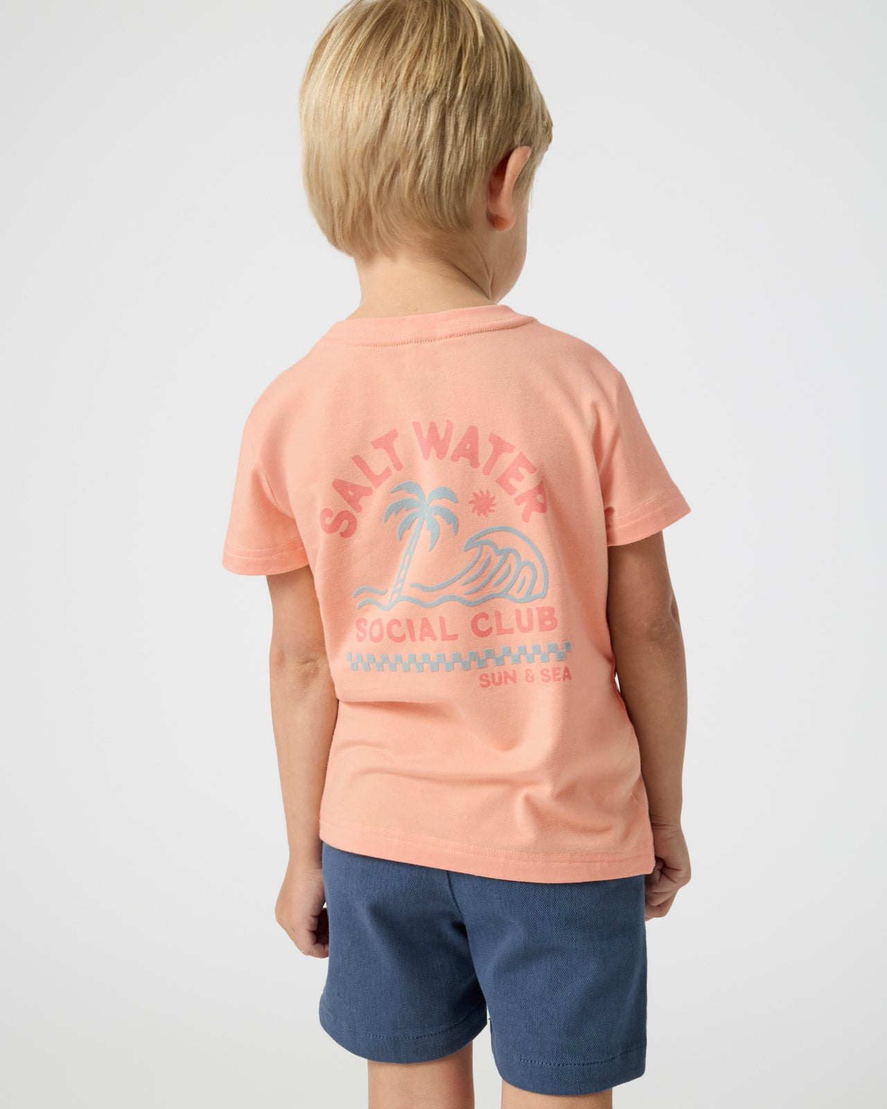 Back view of boy wearing the Salt Water Social Club Relaxed Tee with navy shorts