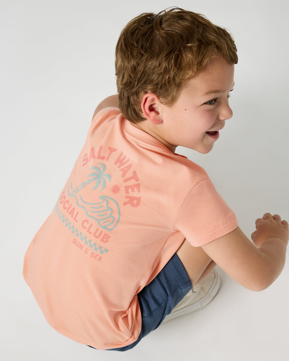Crouching child wearing the Salt Water Social Club Relaxed Tee