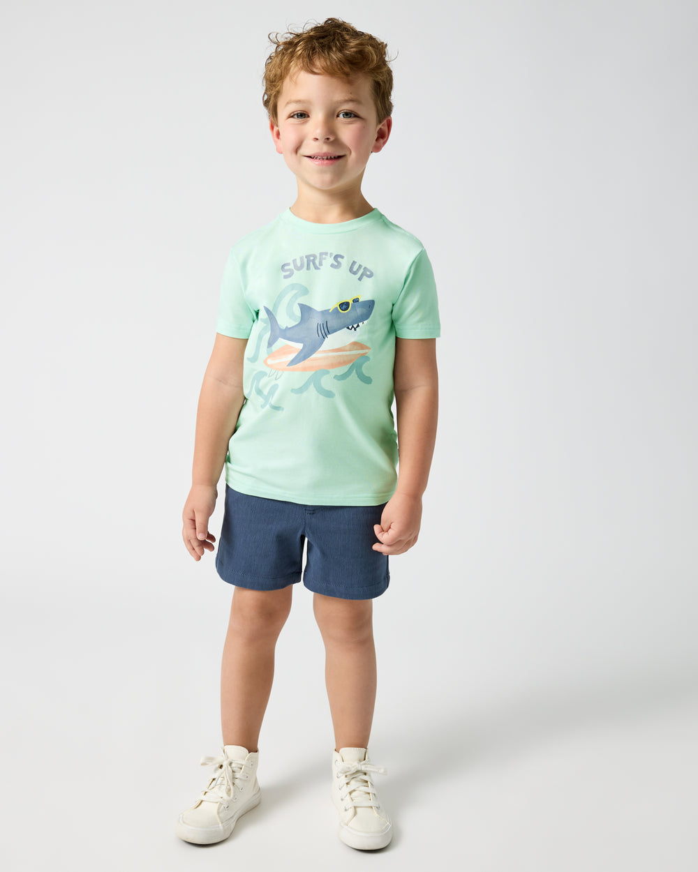 Standing boy wearing the Surf's Up Relaxed Tee with navy shorts