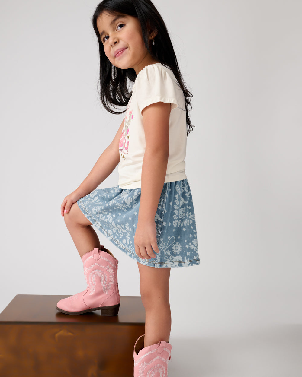 Side view of girl wearing the Howdy Cowgirl Puff Sleeve Tee with pink cowgirl boots