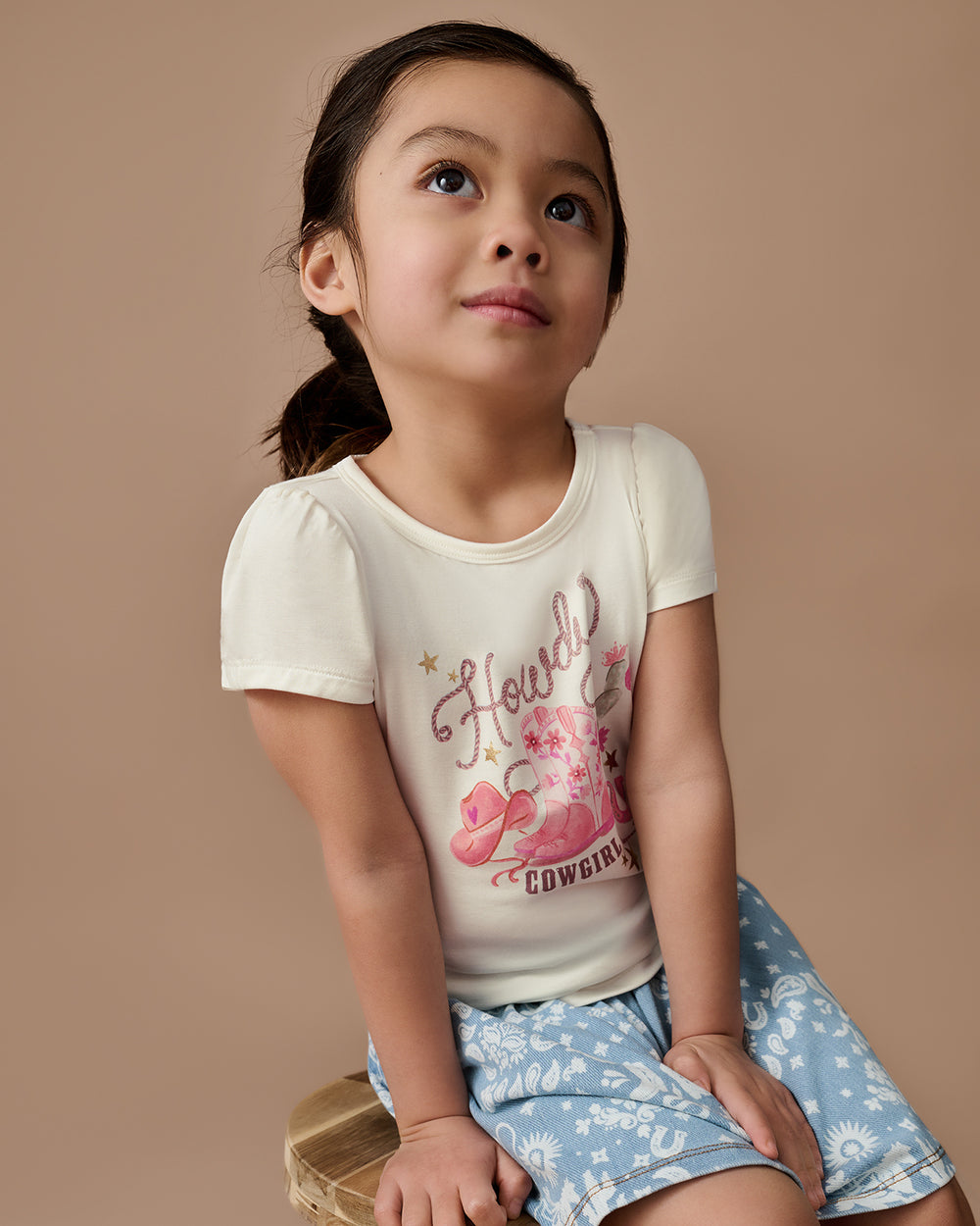 Alternate girl wearing the Howdy Cowgirl Puff Sleeve Tee n a brown background