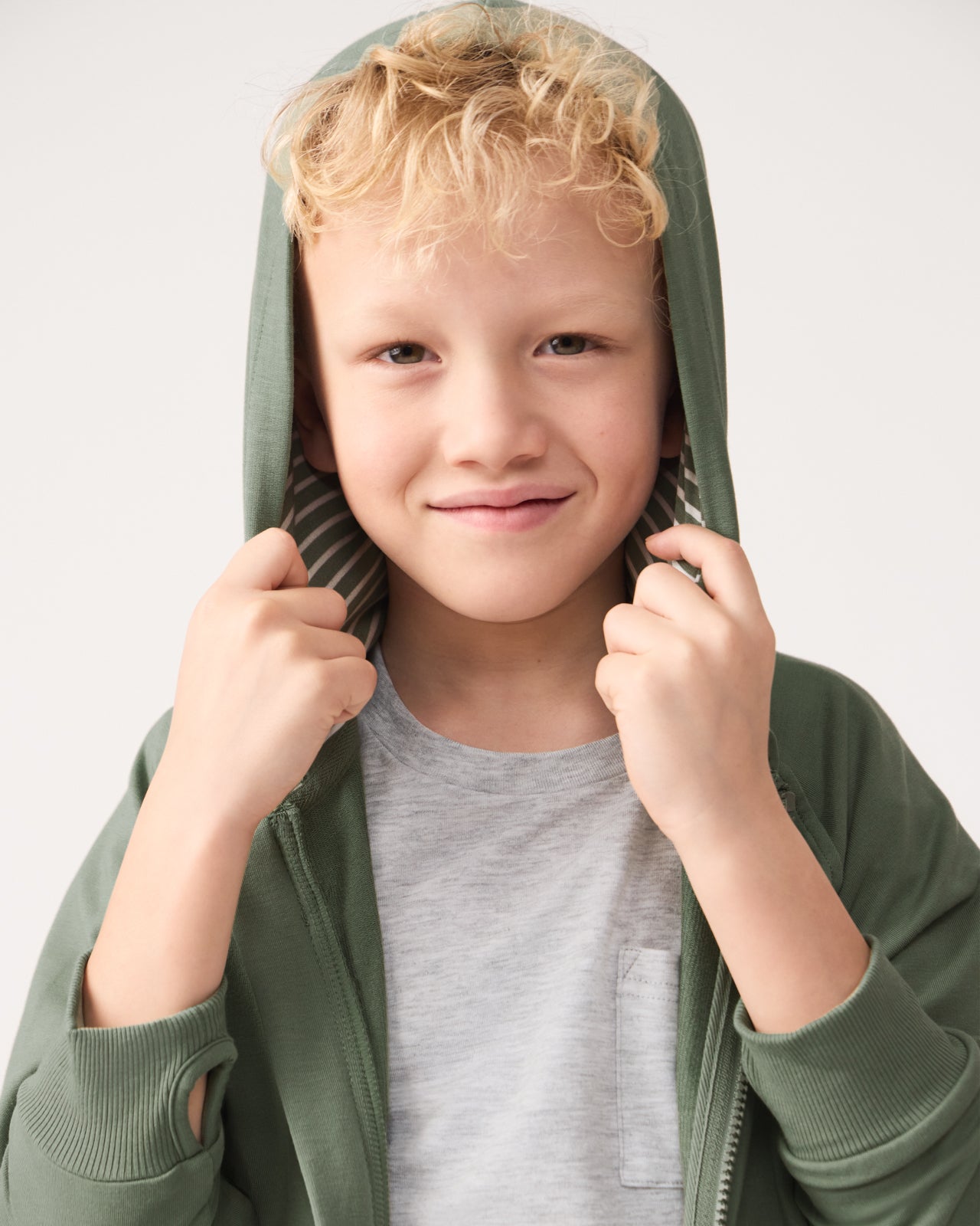 Boy wearing the Moss Zip Hoodie with the hood on