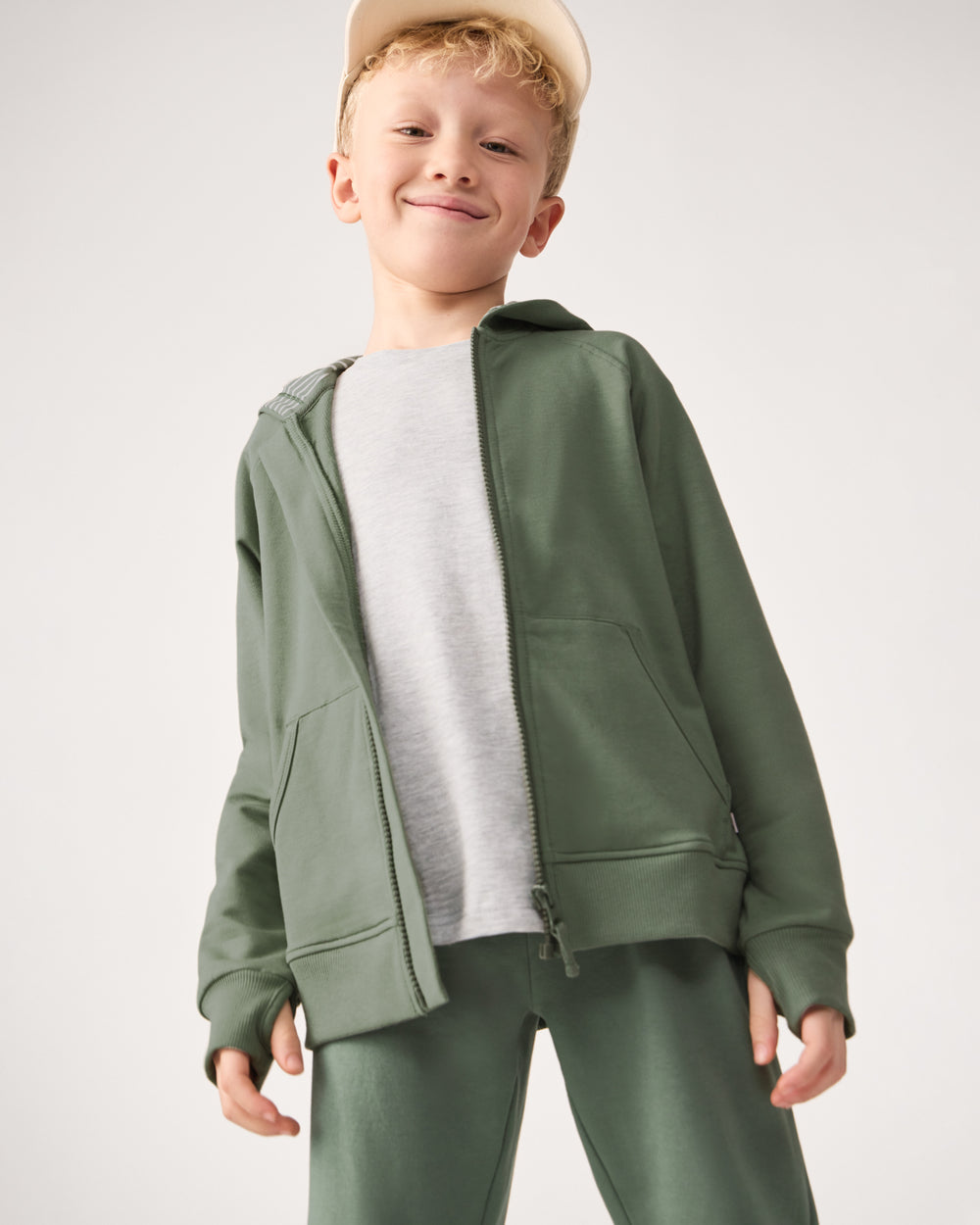 Boy wearing the Moss Zip Hoodie layered over a light gray tee