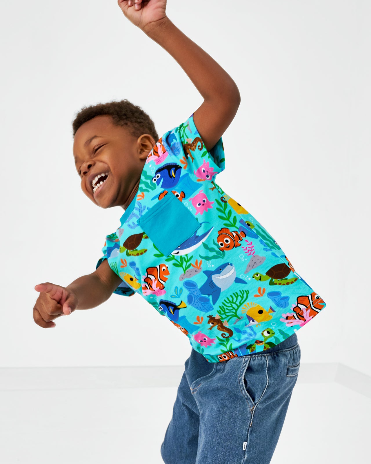 Dancing child wearing the Disney Nemo's Reef Relaxed Pocket Tee with denim joggers