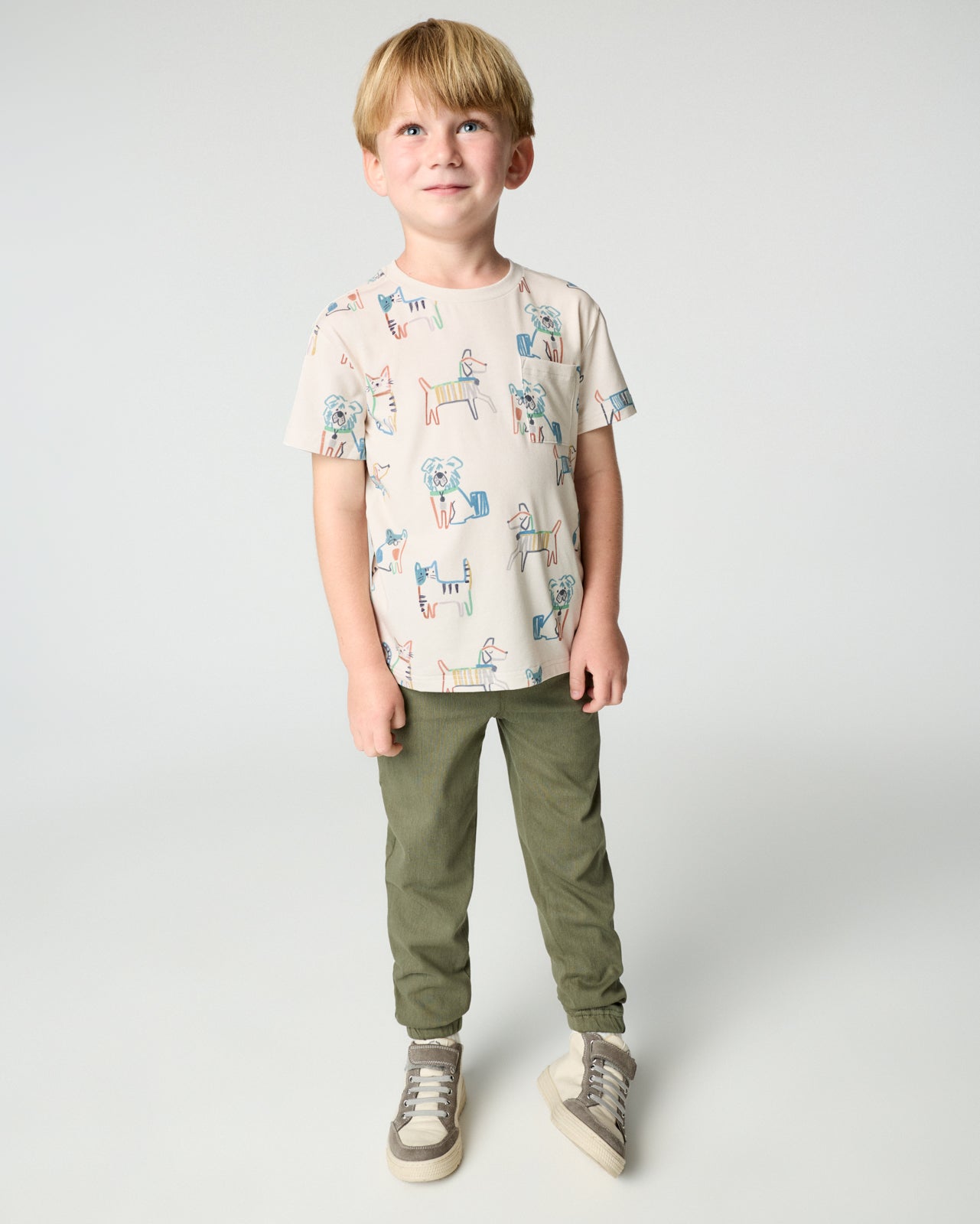 Boy wearing the Whiskers & Wags Relaxed Pocket Tee with green joggers