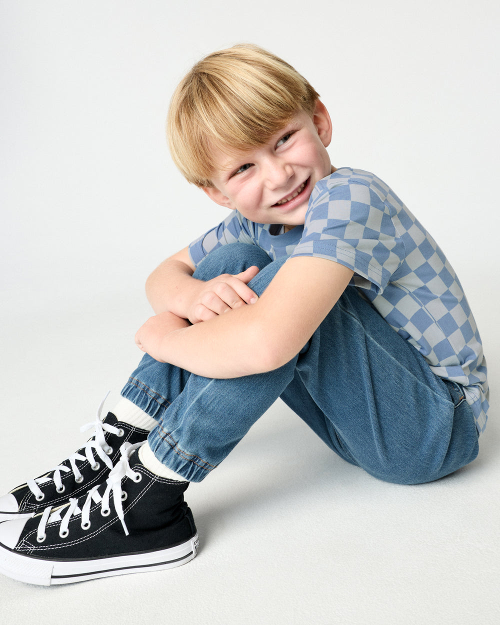 Sitting child wearing the Dusk Blue Checks Relaxed Pocket Tee with denim pants