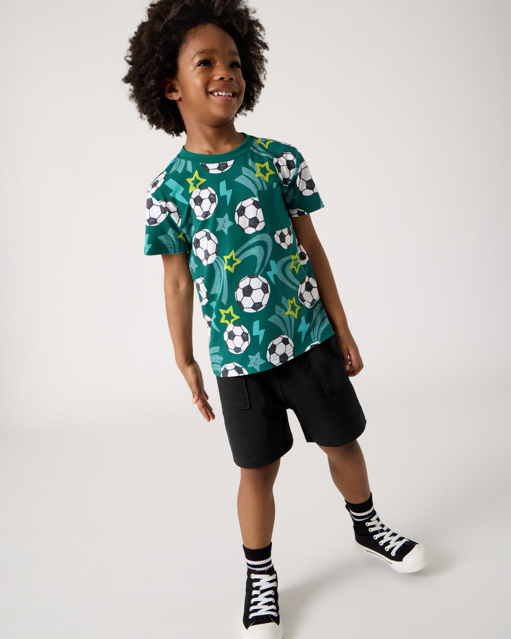 Boy wearing the Soccer Stars Relaxed Pocket Tee with black shorts