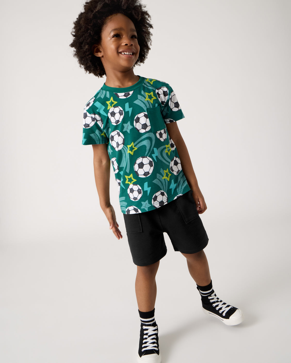 Boy wearing the Soccer Stars Relaxed Pocket Tee with black shorts