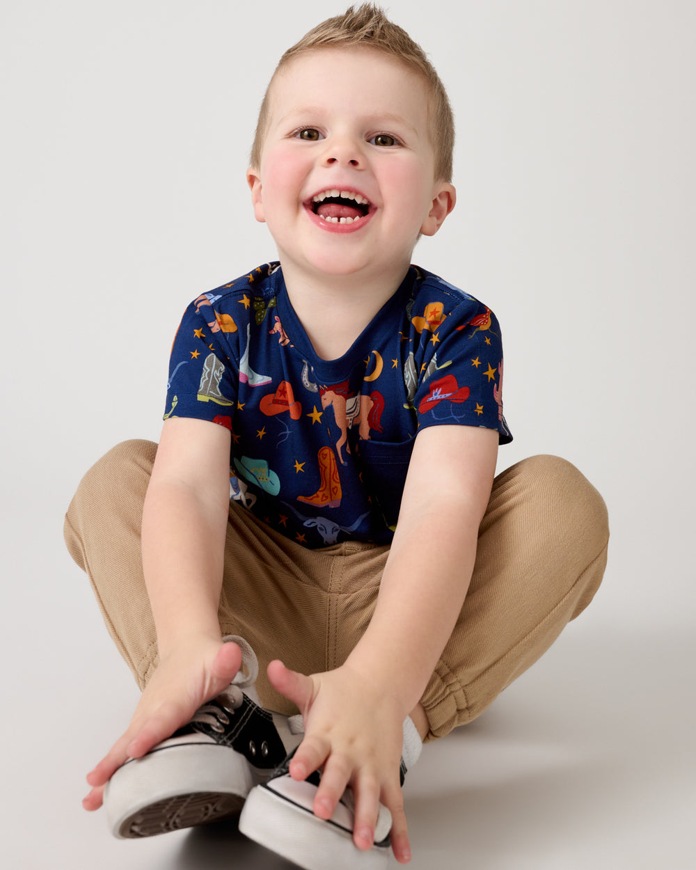 Sitting boy wearing the Blue Rancher Roundup Relaxed Pocket Tee with khaki pants