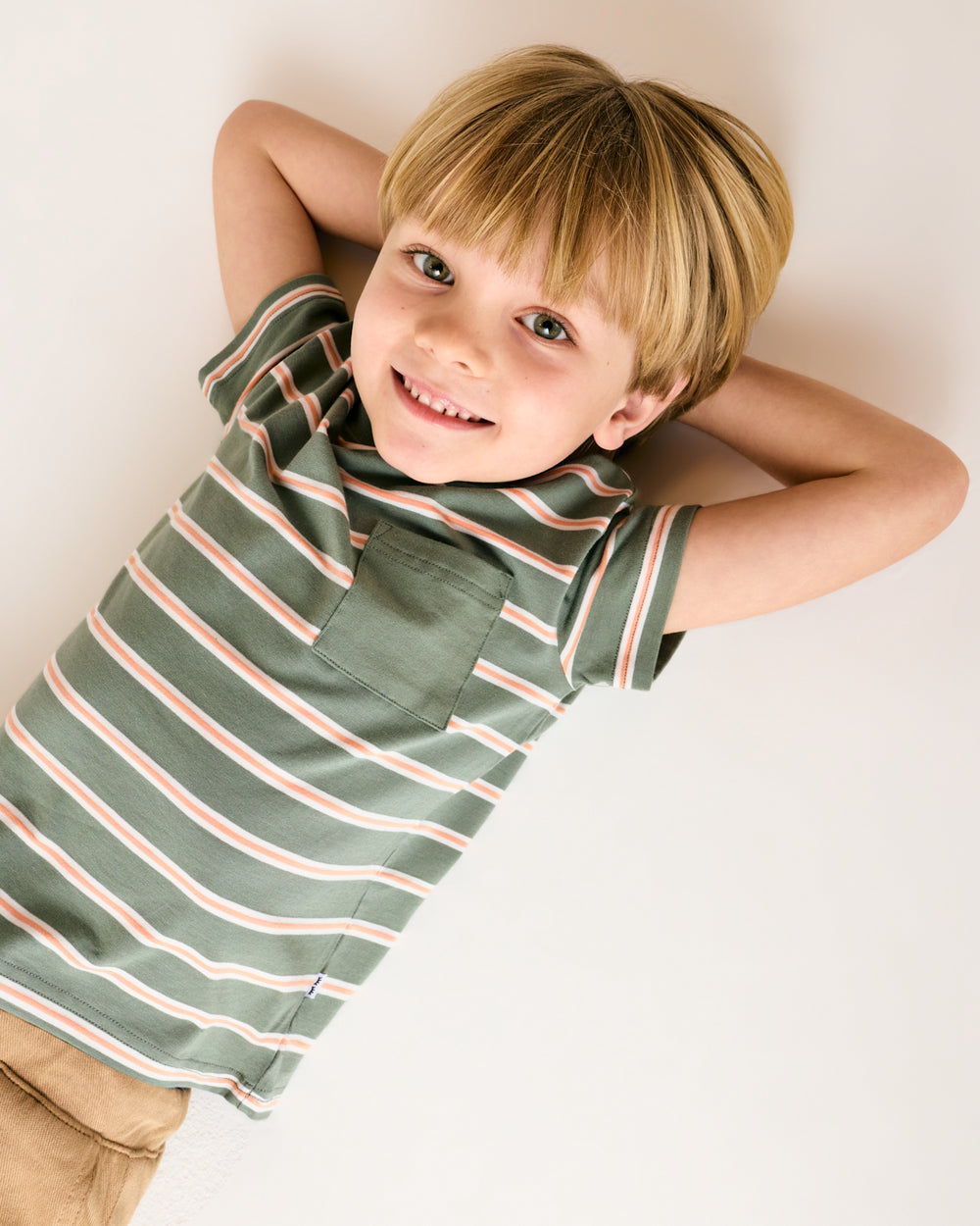 Laying child wearing the Moss Stripe Relaxed Pocket Tee