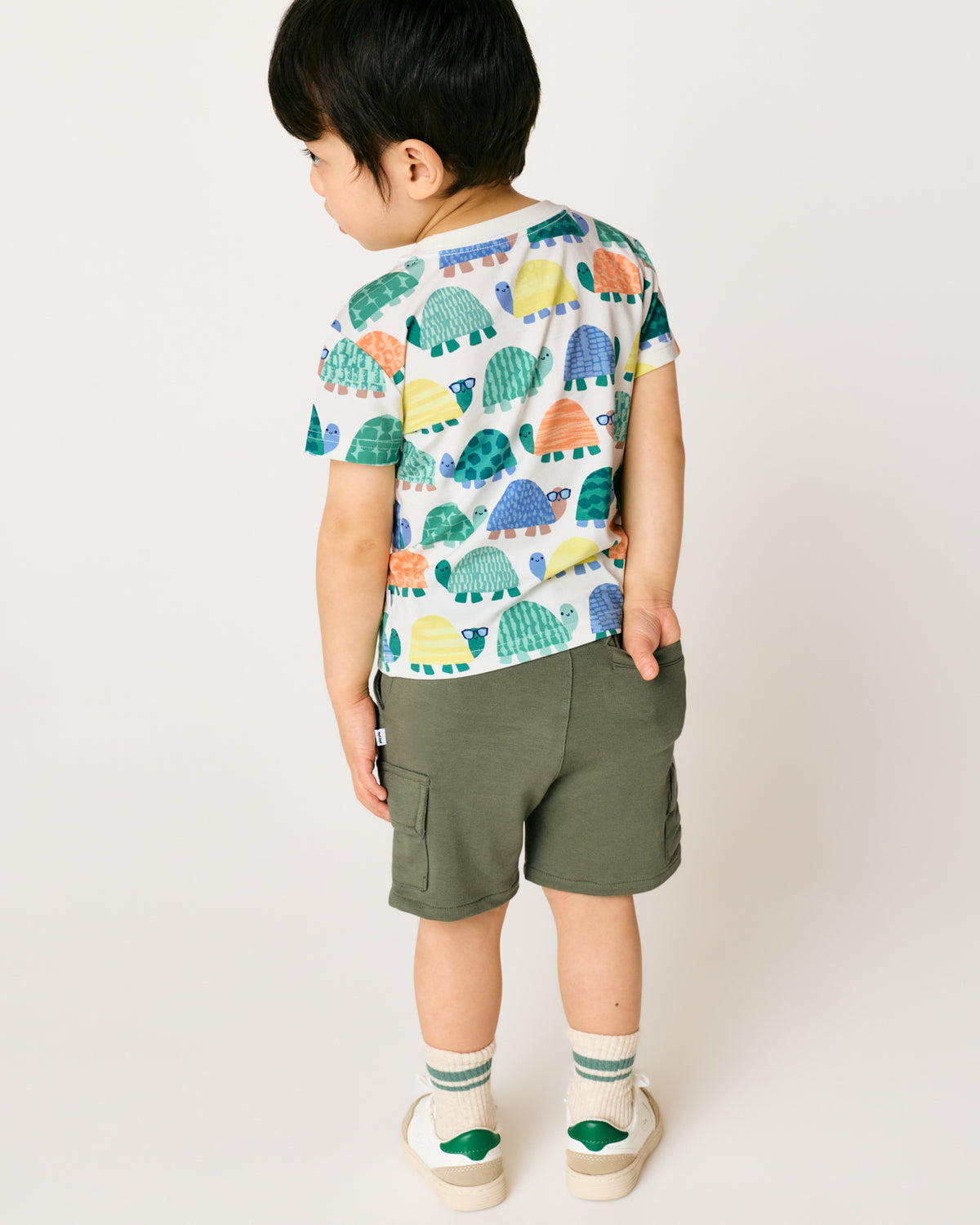 Back view of child wearing the Shell Parade Relaxed Pocket Tee with green shorts
