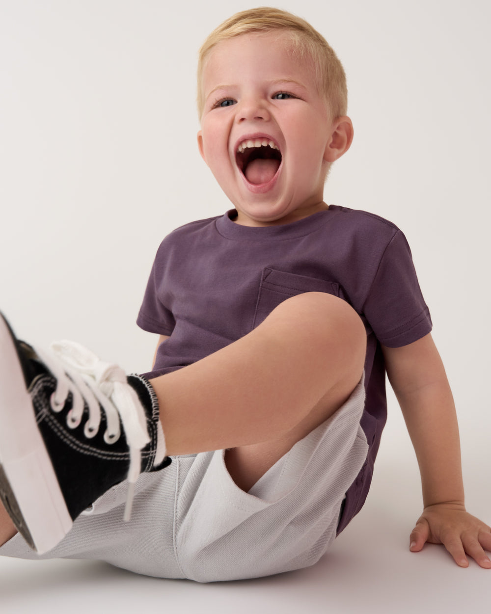 Sitting boy wearing the Vintage Plum Relaxed Pocket Tee with gray shorts