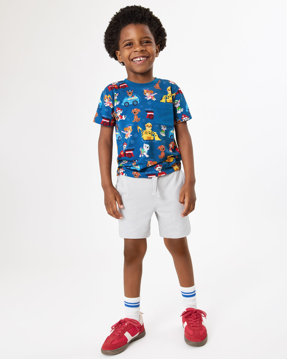 Boy wearing the PAW Patrol Adventure Bay Heroes Relaxed Pocket Tee with gray boys shorts