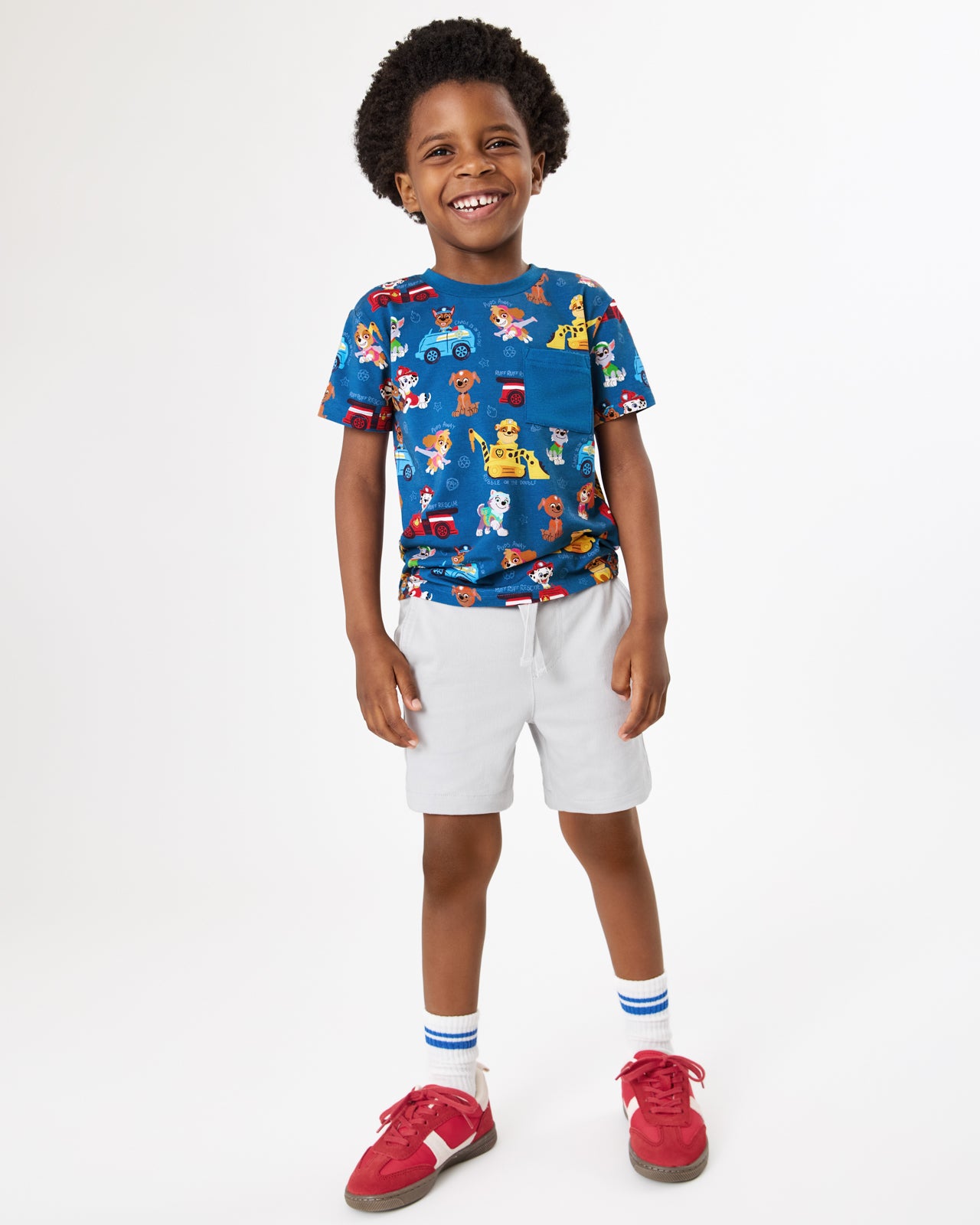 Boy wearing the PAW Patrol Adventure Bay Heroes Relaxed Pocket Tee with gray boys shorts